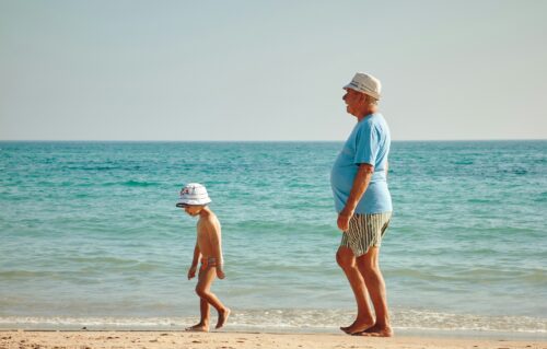 海辺を子供と大人が歩いている画像